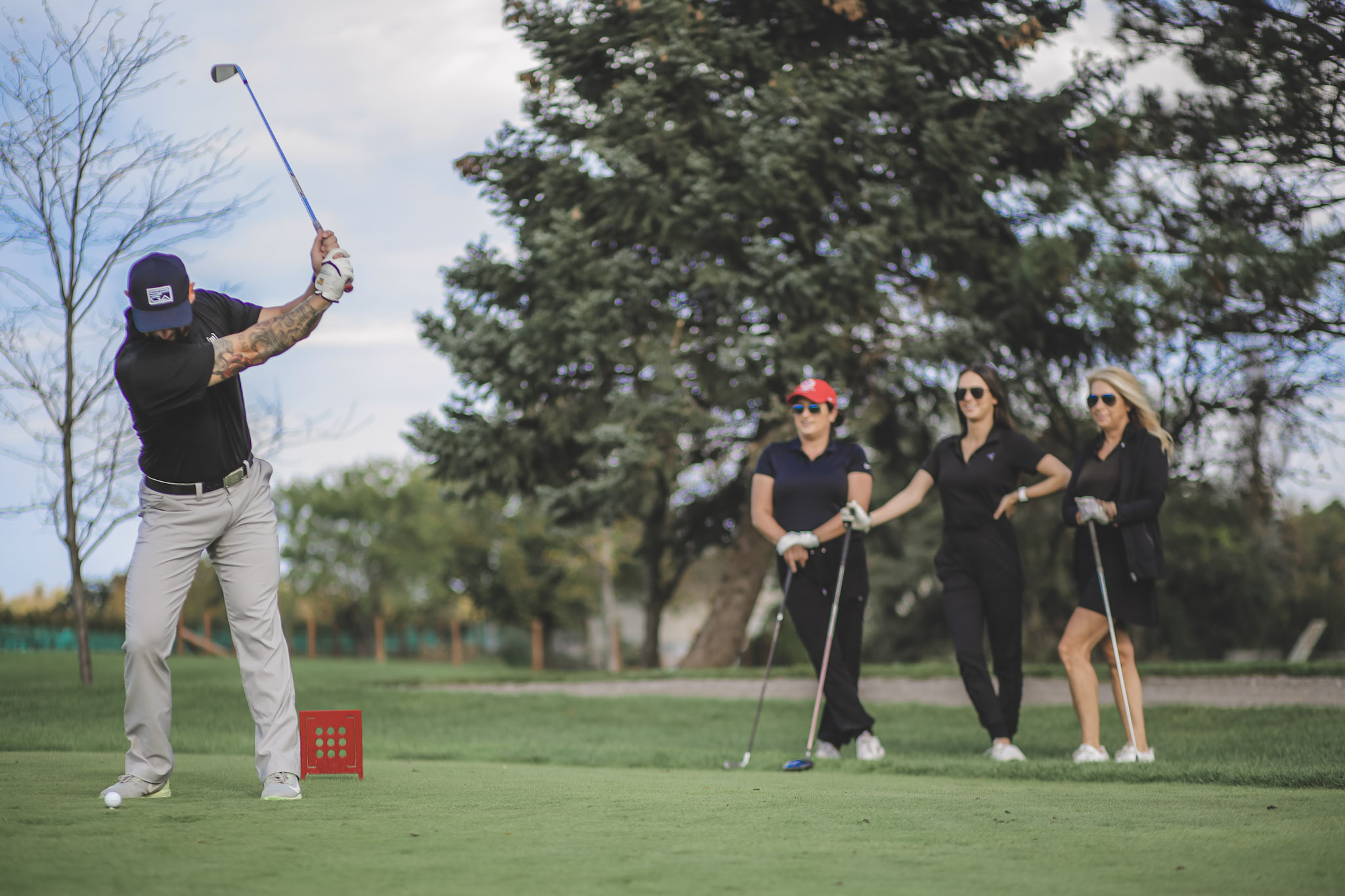 a golfer taking a shot while three people watch